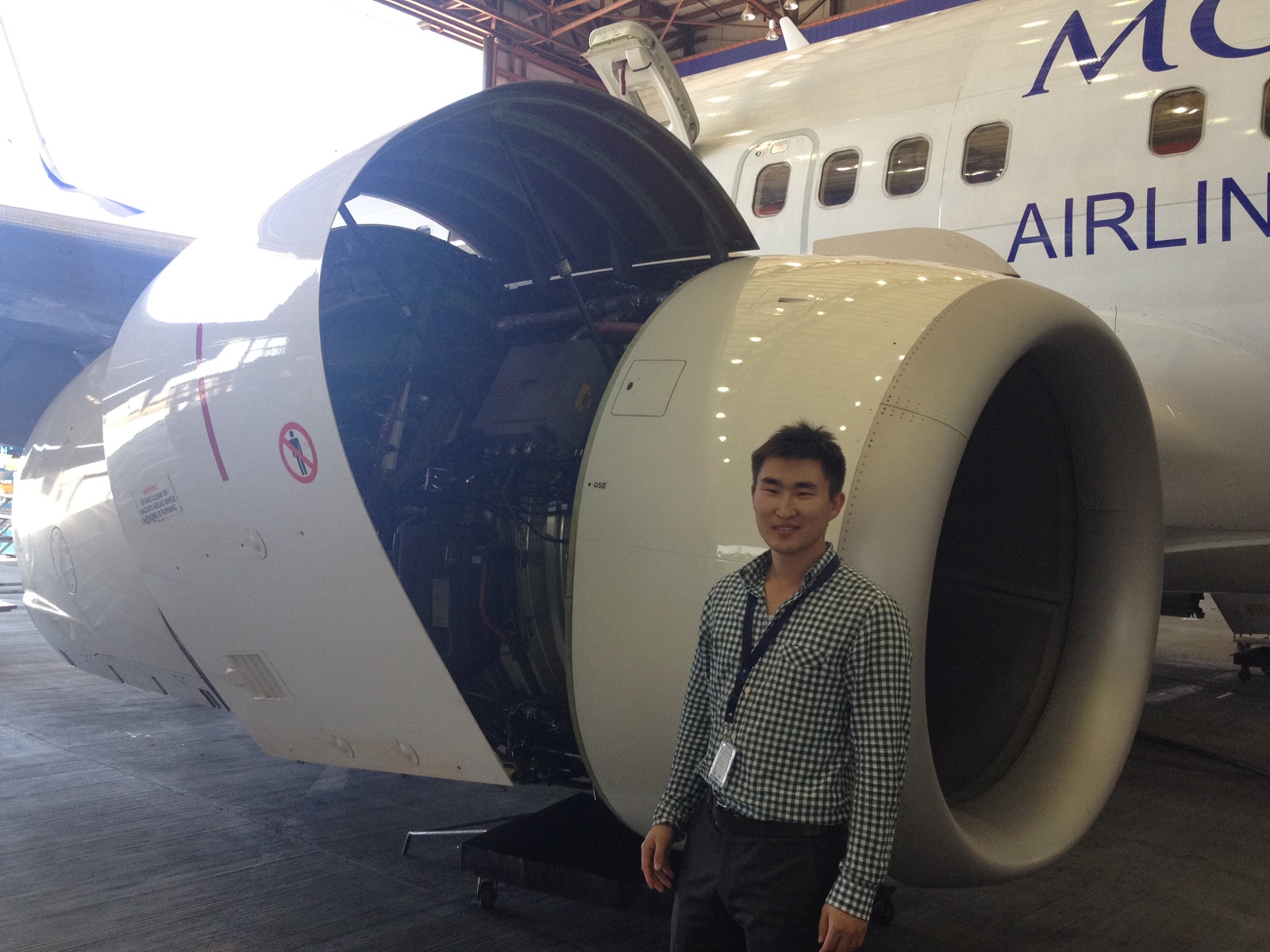 Ider-Od beside a MIAT aircraft engine in a hangar
