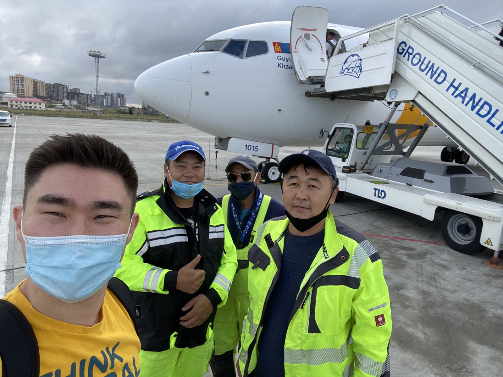 Group selfie beside an aircraft on the tarmac